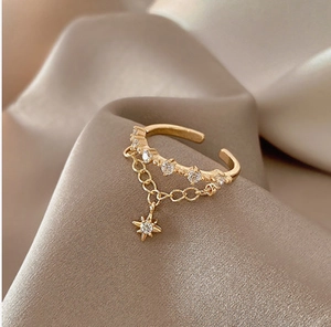 Macro detail of adjustable gold alloy ring featuring star charm and sparkling zircons