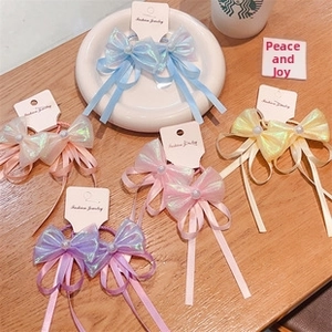 Close-up of five colorful ribbon bow hair ties with pearl accents on wooden background