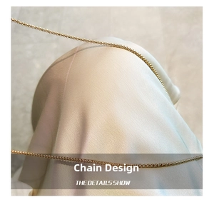 Detailed close-up of a premium gold-plated cross-link chain on soft silk fabric background