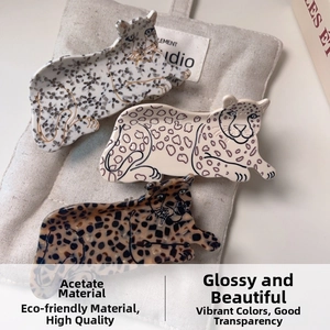 Three acetate hair claws with leopard and tortoiseshell patterns on linen background