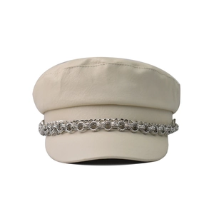 Detail of off-white faux leather newsboy hat featuring triple layered silver metal chains