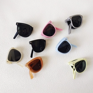 Foldable kids sunglasses in seven vibrant colors displayed on white textured background