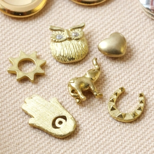 Golden vintage pendant charms with owl, elephant and heart shapes on woven fabric