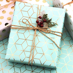 Carta da regalo verde menta con motivi geometrici dorati e decorazione di agrifoglio
