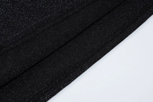 Gros plan sur le tissu noir brillant montrant les coutures et la texture scintillante
