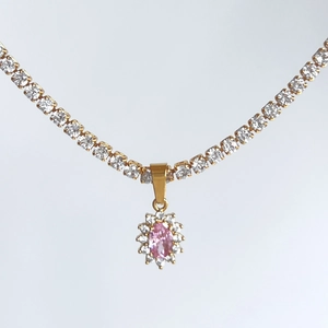 Close-up of gold tennis chain necklace with oval pink stone halo pendant and zircons