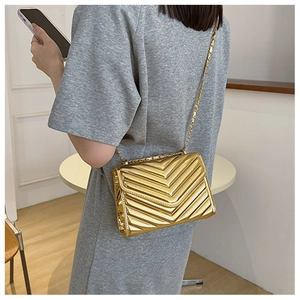 Detail of gold metallic crossbody bag with V-shaped quilting and fine chain strap