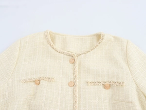 Gros plan du haut en tweed montrant des boutons dorés et la texture tissée de la veste