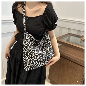 Detailed shoulder view of a black and white leopard print canvas tote bag on a model