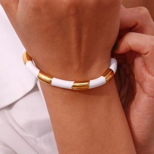 Detailed close-up of gold and white segmented stainless steel bangle on a wrist