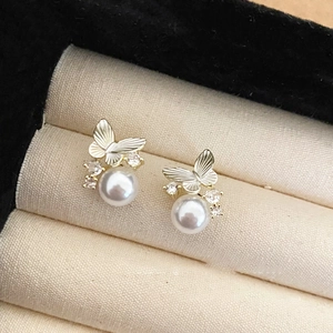 Detail of elegant butterfly pearl earrings with fine gold finish and zircon stones