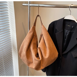 Detailed view of large brown suede tote bag hanging with minimalist half-moon shape design