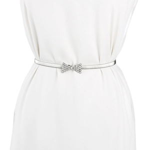 Détail de la ceinture élastique argentée avec boucle nœud en strass sur robe blanche