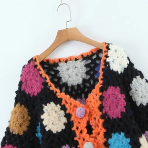 Detail of handmade crochet cardigan with colorful 3D floral patterns and orange trim
