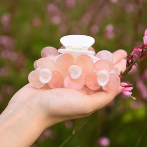 Détail d'une pince à cheveux rose en acétate avec roses sculptées tenue à la main