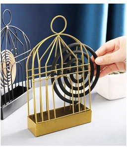 Detail showing hand placing a mosquito coil inside a birdcage iron incense holder