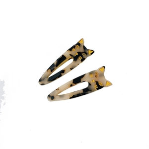 Set of two tortoise shell cat-shaped hair clips with gold details on white background