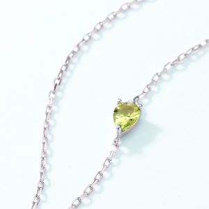 Macro shot of S925 sterling silver necklace with a pear-cut green gemstone pendant