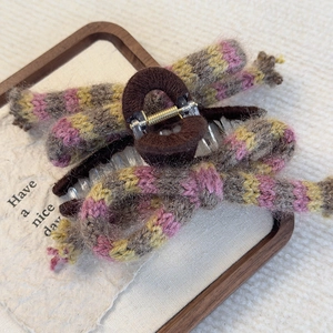 Close-up of striped knitted bow hair claw clip with golden metal spring detail