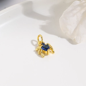 Gold spider pendant featuring heart-shaped blue zircon stone on a white display tray