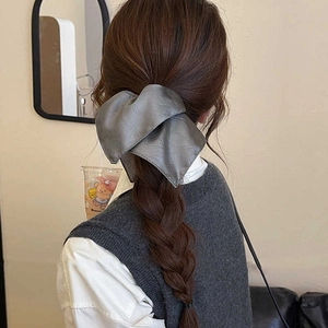 Deep grey leather texture bow hair tie shown on a braided hairstyle in a lifestyle setting