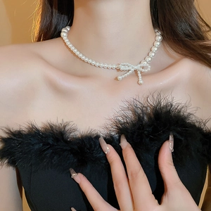 Elegant pearl choker necklace featuring a delicate hand-woven pearl bow charm for women