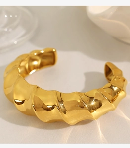 Macro shot of gold cuff bracelet featuring irregular wavy molten lava texture surface