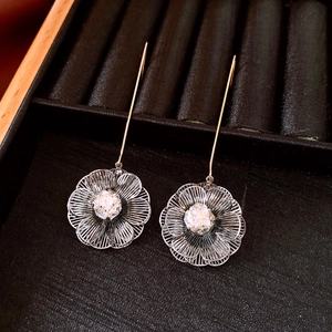 Détail de boucles d'oreilles pendantes plaquées or 18K avec pétales de fleurs en argent
