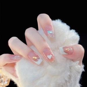 Detail of short square press-on nails with nude blush color and white heart pattern