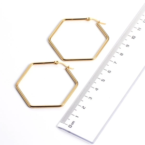 Detail view of 5cm gold geometric hexagonal hoop earrings with a ruler for size reference