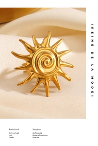 Detailed close-up of golden sun spiral pattern ring on elegant white fabric