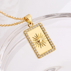 Macro d'un pendentif doré rectangulaire avec motif soleil et zircons sur chaîne en O