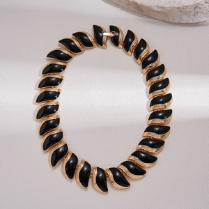 Vue macro du collier feuilles en émail noir avec détails dorés et fermoir de sécurité