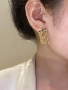 Detail von 14k vergoldeten Quastenohrringen mit Zirkonia an einem weiblichen Modell