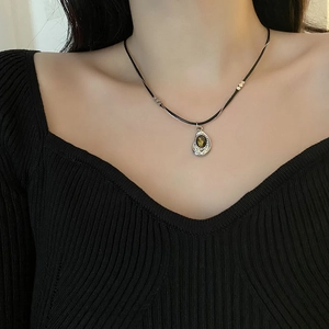 Retro double-layer tiger eye stone necklace with vintage metal pendant on black knitwear