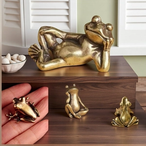 Detail of four vintage brass frog figurines showing artistic poses and antique finish texture
