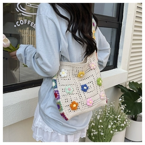 Detailed view of colorful crochet flower appliques on a cream handmade woven tote bag