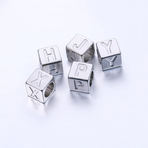 Détail macro de perles cubes de 7mm en acier inox avec lettres gravées H, X, J, P et Y