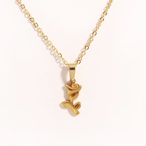 Macro detail of golden rose flower pendant with fine chain on white background