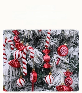 Close-up of red and white candy cane ornaments with glitter hanging on a snowy Christmas tree