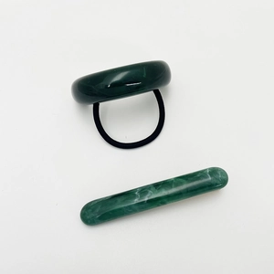 Detailed view of dark green resin hair tie and hair clip set with marble texture finish