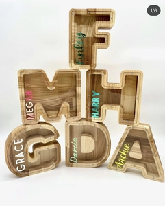 Detail of wooden letter piggy banks with acrylic panels and custom name stickers