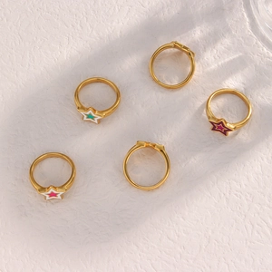 Artistic layout of five gold star rings with colorful enamel detailing on textured surface