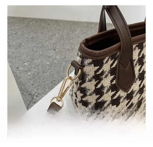 Gros plan détaillé du crochet en métal doré et de la bandoulière en cuir du sac pied-de-poule