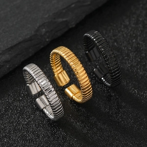 Macro view of textured C-shape stainless steel rings in silver, gold, and black colors