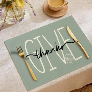 Detail of sage green Thanksgiving placemat with Give Thanks pumpkin and maple leaf print