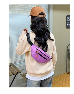 Purple oxford crossbody bag with adjustable black buckle strap shown in a cafe setting