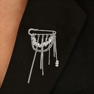 Close-up of industrial silver tassel brooch with metal chain fringe on a black blazer