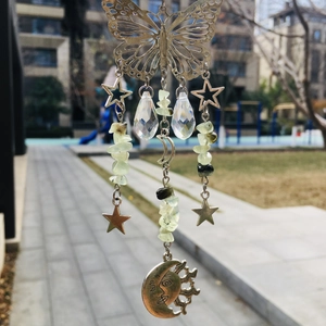 Detail of butterfly suncatcher with crystal drops, green stones and moon pendant