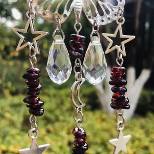 Macro shot of silver suncatcher with butterfly and moon charms plus red garnet beads